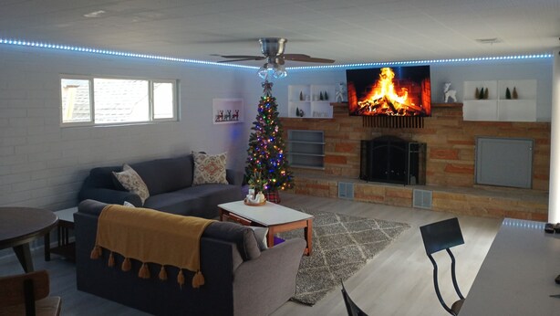A living room with a fireplace, a Christmas tree, and a flat-screen TV.