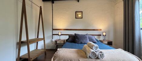 Une chambre avec une échelle en bois, un lit avec une literie bleue, une tête de lit en bois et une table de chevet avec une lampe.