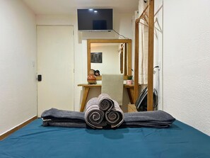 A bedroom with a bed, a TV, a mirror, a wooden desk, and a door. - Discover Condesa (Mexico City)