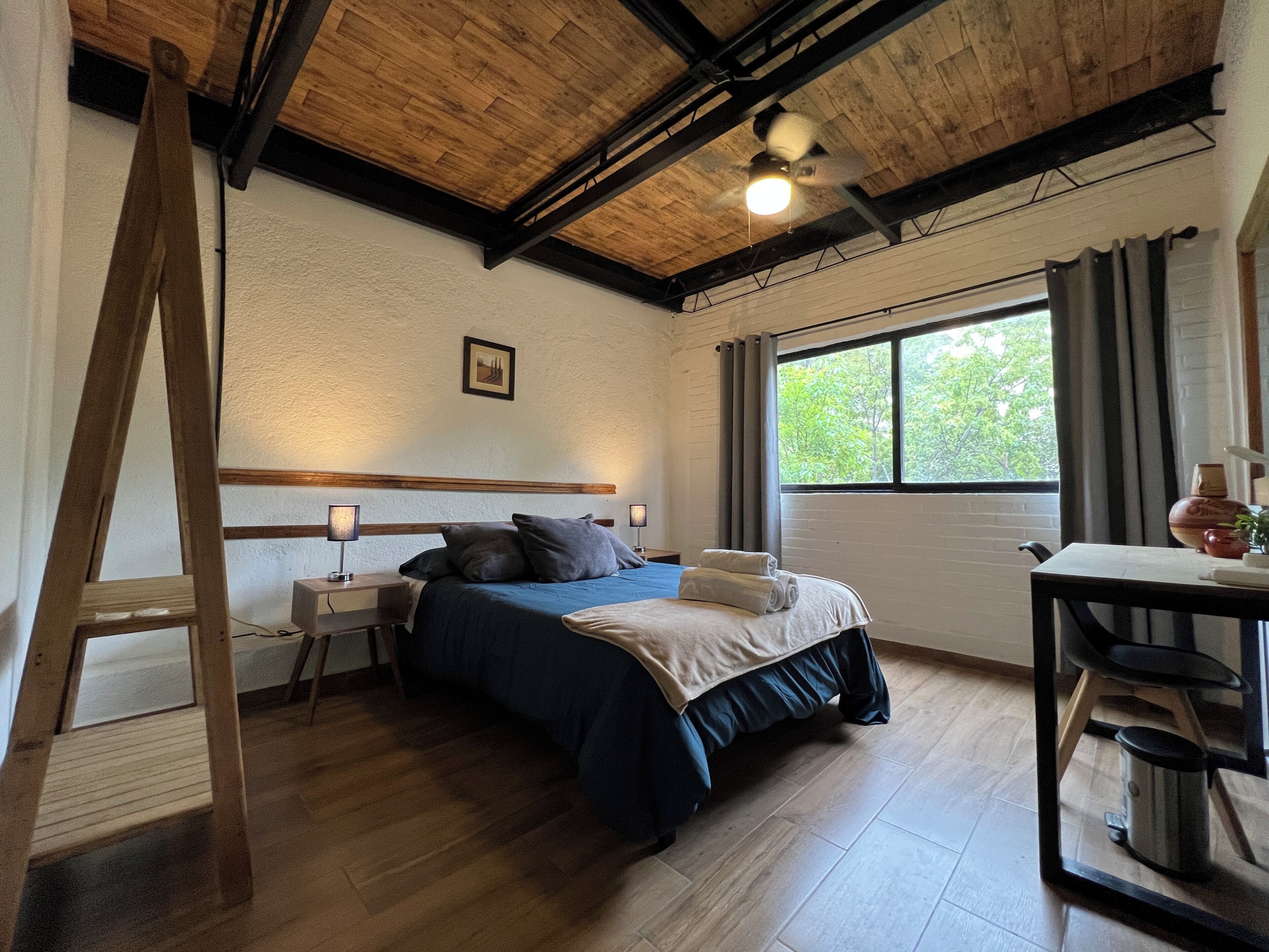 A room with a bed, a desk, a window, and a ceiling fan.