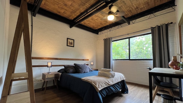 A room with a bed, a desk, a window, and a ceiling fan. - Discover Condesa (Mexico City)
