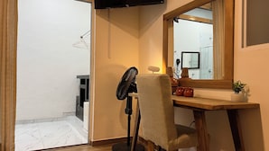 A room with a wooden desk, a chair, a standing fan, a television mounted on the wall, and a mirror. - Discover Condesa (Mexico City)