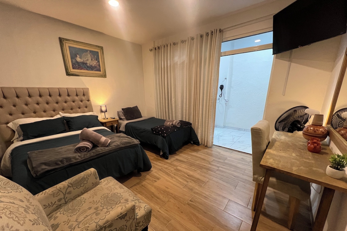 A hotel room with a bed, two bedside tables, a chair, a desk, a television, and a sliding glass door.