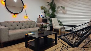 A living room with a sofa, a coffee table, a round mirror, a chair, and a potted plant. - Discover Condesa (Mexico City)