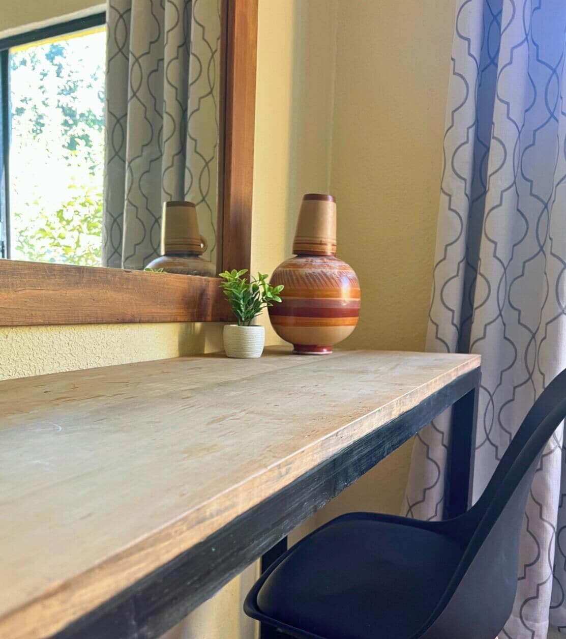 A wooden shelf with a potted plant and a vase.