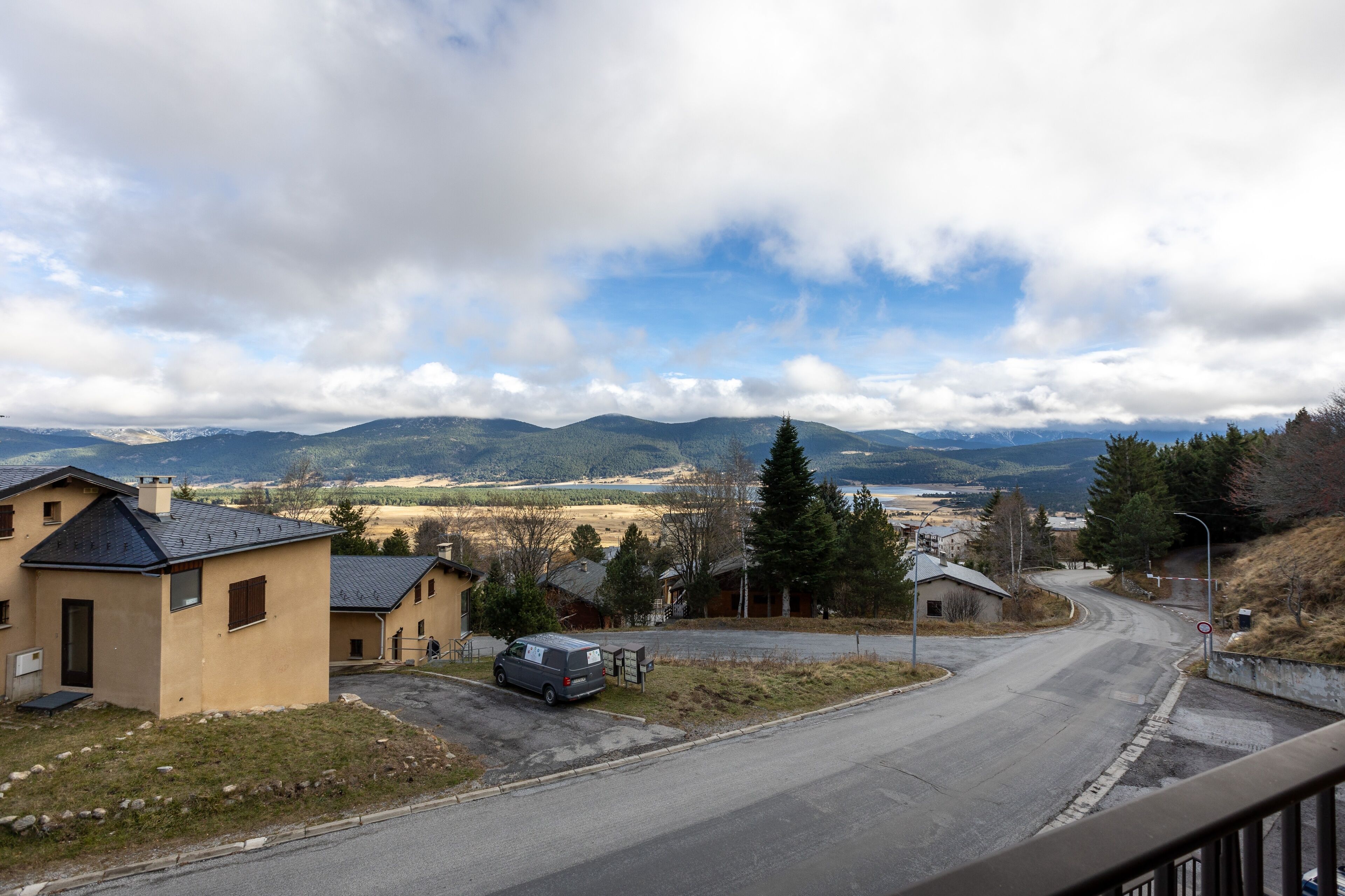 Eine Wohnstraße mit Häusern, einem Lieferwagen und freiem Blick auf ferne Berge.