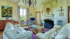 Una sala de estar con chimenea, sofás de cuero, una mesa de centro de vidrio y una araña.