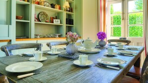 Una mesa de comedor dispuesta con platos, tazas y una tetera, rodeada de sillas.