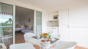 A small, bright room with a balcony, a kitchenette, and a dining area with white furniture. - Tropicanavibes - Vue mer à Sainte-Luce (Sainte-Luce)