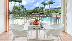 A balcony with a table set for two, overlooking a pool and palm trees. - Tropicanavibes - Vue mer à Sainte-Luce (Sainte-Luce)