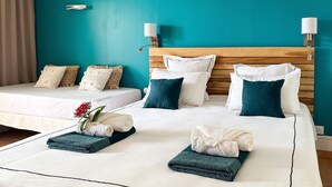 A hotel room with two beds, teal walls, white bedding, and a wooden headboard.