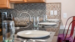 Une cuisine avec des meubles en bois, un dosseret carrelé et un coin repas avec une table mise pour deux personnes.