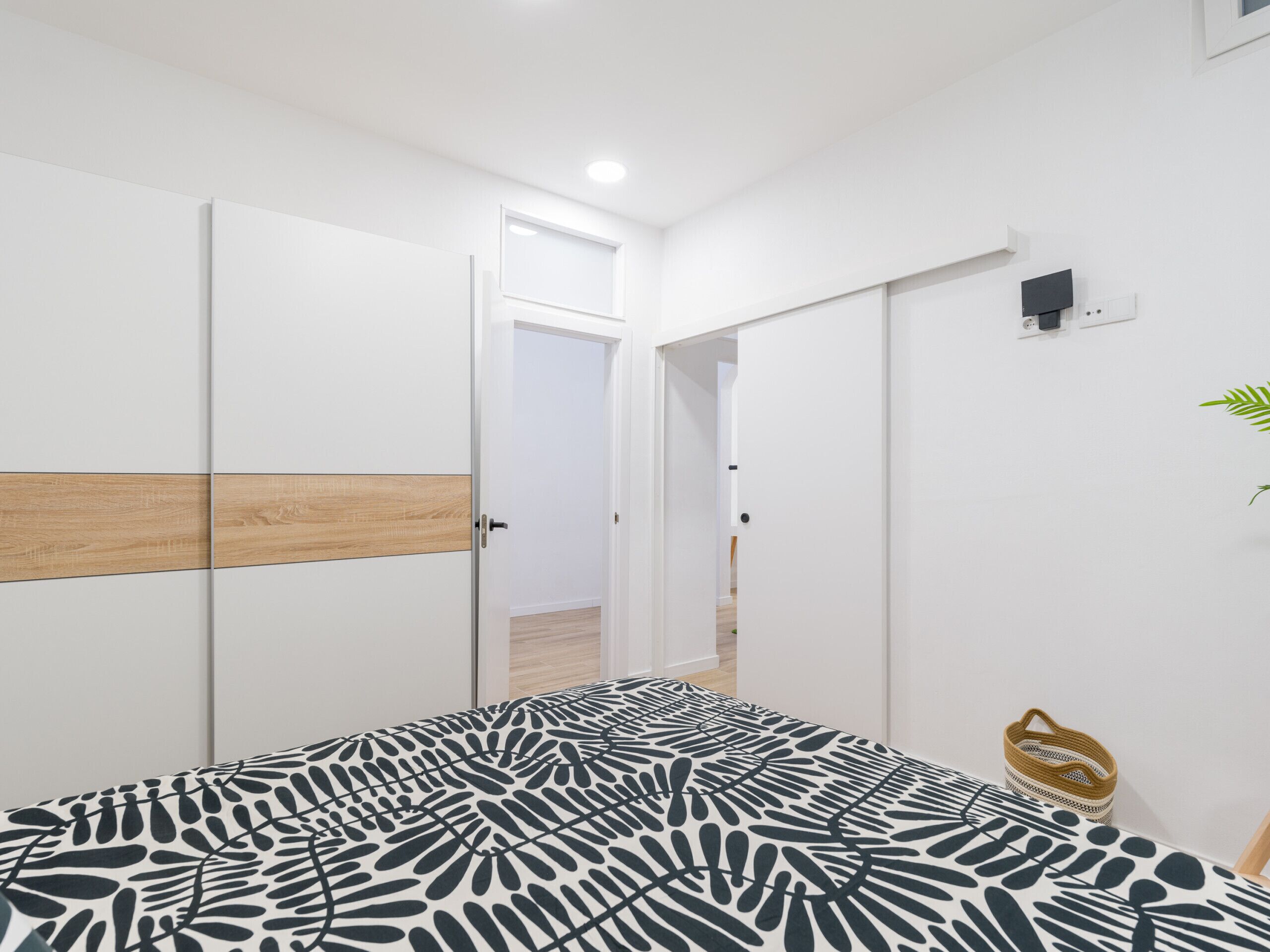 A bedroom with a bed, a wardrobe, and a small plant.