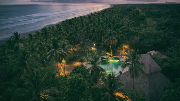 Ein Resort mit Pool, umgeben von Palmen, mit Blick auf Strand und Meer.