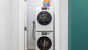 A front-loading washer and dryer unit with a Tide detergent dispenser on top.