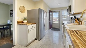 A modern kitchen with a refrigerator, microwave, and wooden countertop. - 2BR Family Charmer Duplex near Drake (Des Moines)