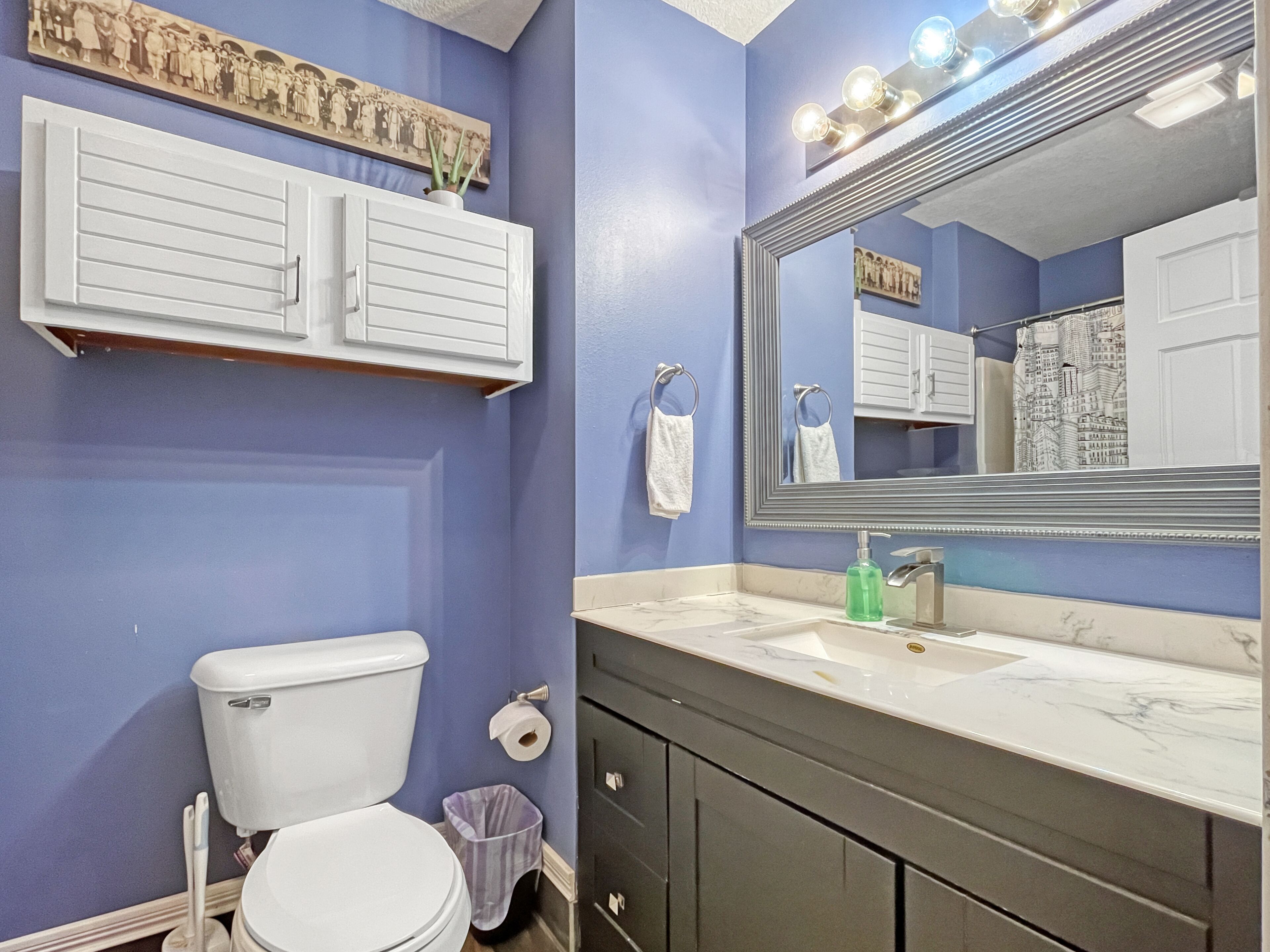 Une salle de bain comprenant des toilettes, un lavabo, un meuble-lavabo et un grand miroir.