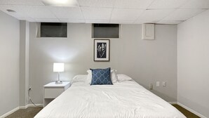 A hotel room with a single bed, a nightstand, a wall-mounted lamp, and a framed picture above the bed. - Family Friendly 3 BR 2 Bath Duplex Sleeps 9! (Des Moines)