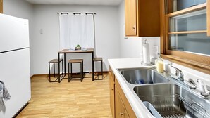 A compact kitchen with a refrigerator, wooden cabinets, a sink, and a window. - Family Friendly 3 BR 2 Bath Duplex Sleeps 9! (Des Moines)