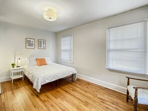 Une chambre à coucher avec un lit, une table de chevet, une lampe et une chaise.
