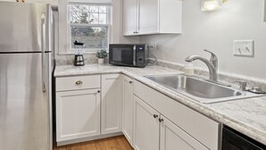 A modern kitchen with white cabinets, stainless steel appliances, a built-in microwave, and a sink with a faucet.