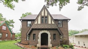 A two-story brick house with a steeply pitched roof and a central entrance with a decorative archway.