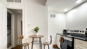 Una cocina funcional con estufa, una pequeña mesa de comedor y dos sillas.