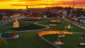 Un parque con un sendero serpenteante, esculturas iluminadas y una gran estructura esférica.