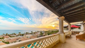 Ein Balkon mit Meer- und Stadtblick, ausgestattet mit einer Pergola, Sitzgelegenheit und einem Pool.