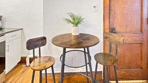 A small dining area with a round wooden table, two chairs, and a potted plant.