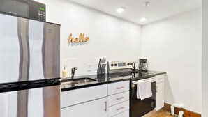 A modern kitchen with stainless steel appliances, a wooden backsplash, and a 'hello' sign on the wall.