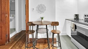 Een moderne keuken met een houten eettafel en krukken, een koffiezetapparaat en een inbouwoven.
