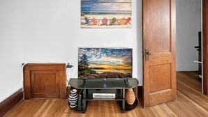 Een kamer met een houten deur, een klein kastje en een televisie waarop een strandafbeelding te zien is.