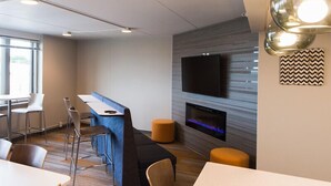 A modern lounge area with a bar, seating, a fireplace, and a flat-screen TV. - Stay in the heart of downtown! Walk to Casey's Center, restaurants, and nightlife. Enjoy free parking and all the comforts of home. (Des Moines)