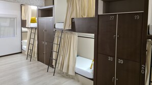 Un dormitorio con literas, una escalera y taquillas numeradas.