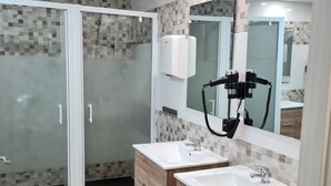 Un baño moderno con dos lavamanos, una cabina de ducha de vidrio y un espejo grande.