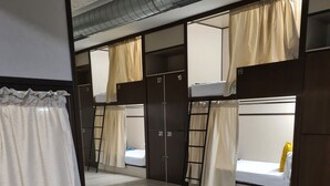 Un dormitorio con literas, suelo de madera y cortinas.