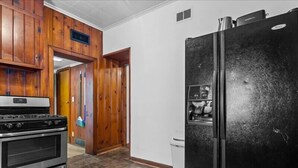 A kitchen with wooden cabinets, a stainless steel stove, and a black refrigerator. - 1BR Residence With Vast Backyard (Des Moines)