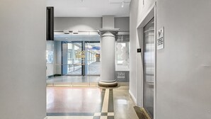 A modern hallway with a glass door entrance, a marble column, and a sign indicating the location. - Beautiful 2BR/2BA in Bldg connected to Skywalk (Des Moines)