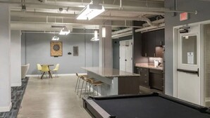 A modern indoor space with a pool table, bar area, and seating.