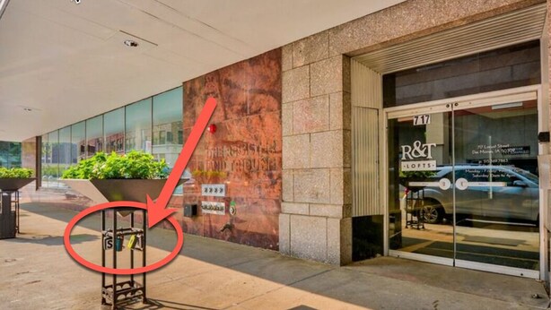 A hotel entrance with a large glass facade, a visible parking area, and a sign for R&T Lofts.