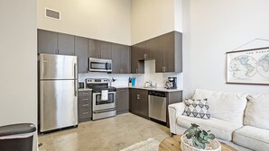 A compact kitchen with modern appliances, a dining area with a sofa, and a coffee machine.