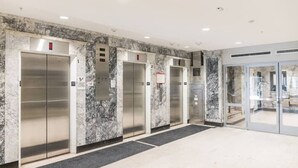 A modern elevator area with marble walls and a glass door entrance.