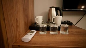 A wooden shelf with a white digital device, four clear glasses of water, and two white mugs. - ATAKUM AYKA OTEL (Atakum)