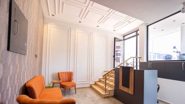 A modern interior with a staircase, orange armchairs, and a view through a large window. - ATAKUM AYKA OTEL (Atakum)