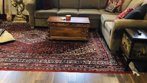 Een woonkamer met een bank, een bijzettafeltje en een kamerbreed tapijt.