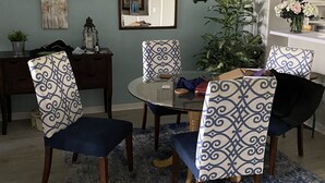 A dining room with a round glass table, four patterned chairs, a decorative mirror, and a 'FAMILY' sign on the wall. - Golf Excellence! Make it yours! Available Nov-Dec 20. (Naples)