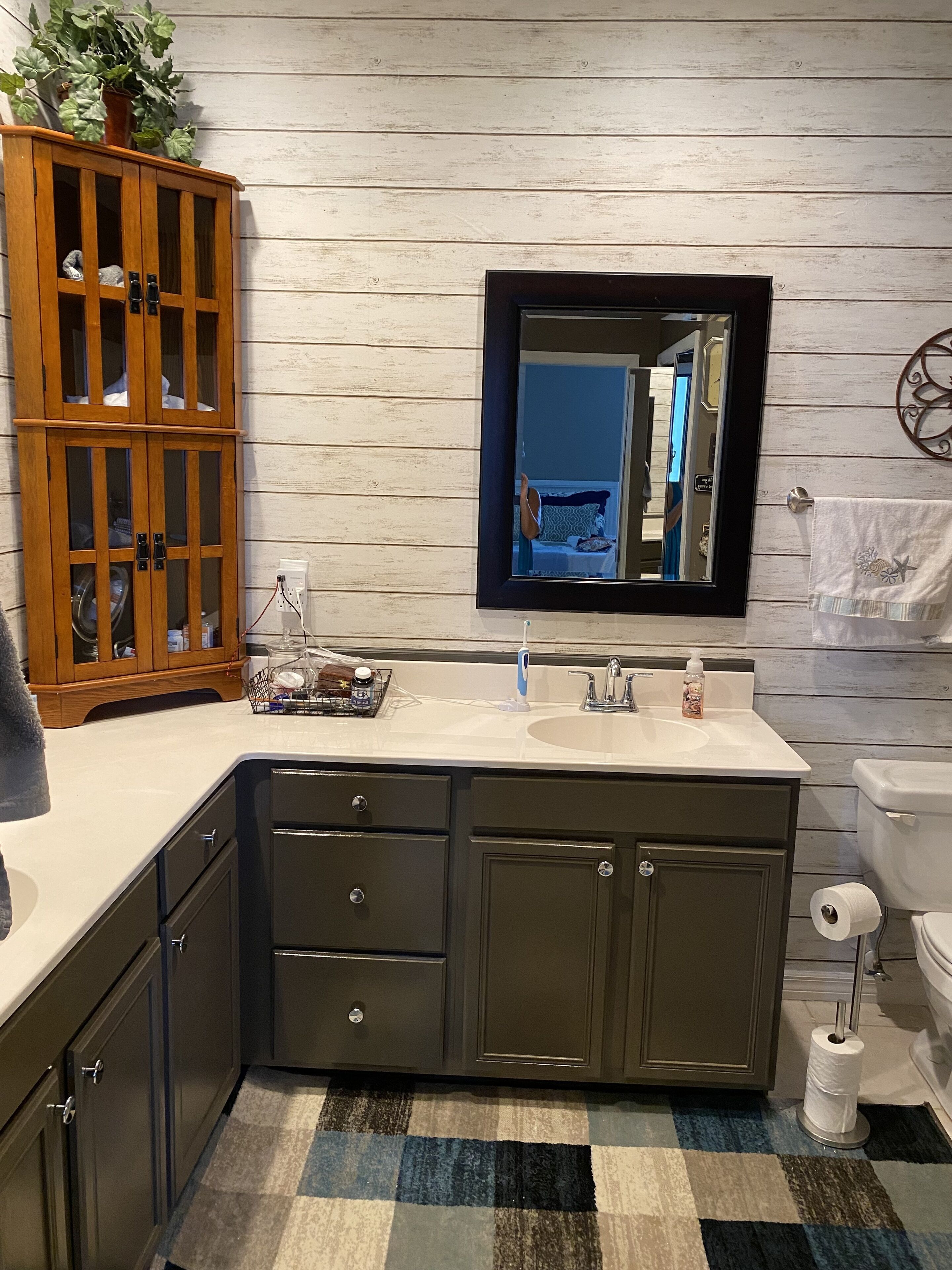 A bathroom with a wooden cabinet, a sink, a mirror, and a toilet.