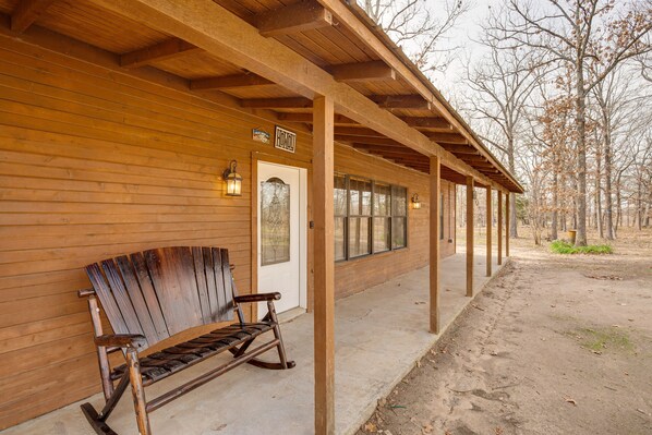 Un bâtiment en bois doté d’un porche couvert, d’un banc et d’une porte sur laquelle est apposée une enseigne.