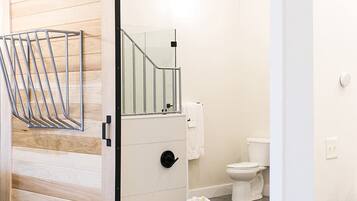 Un baño moderno con puerta corredera de madera, cabina de ducha de cristal, inodoro y bañera.